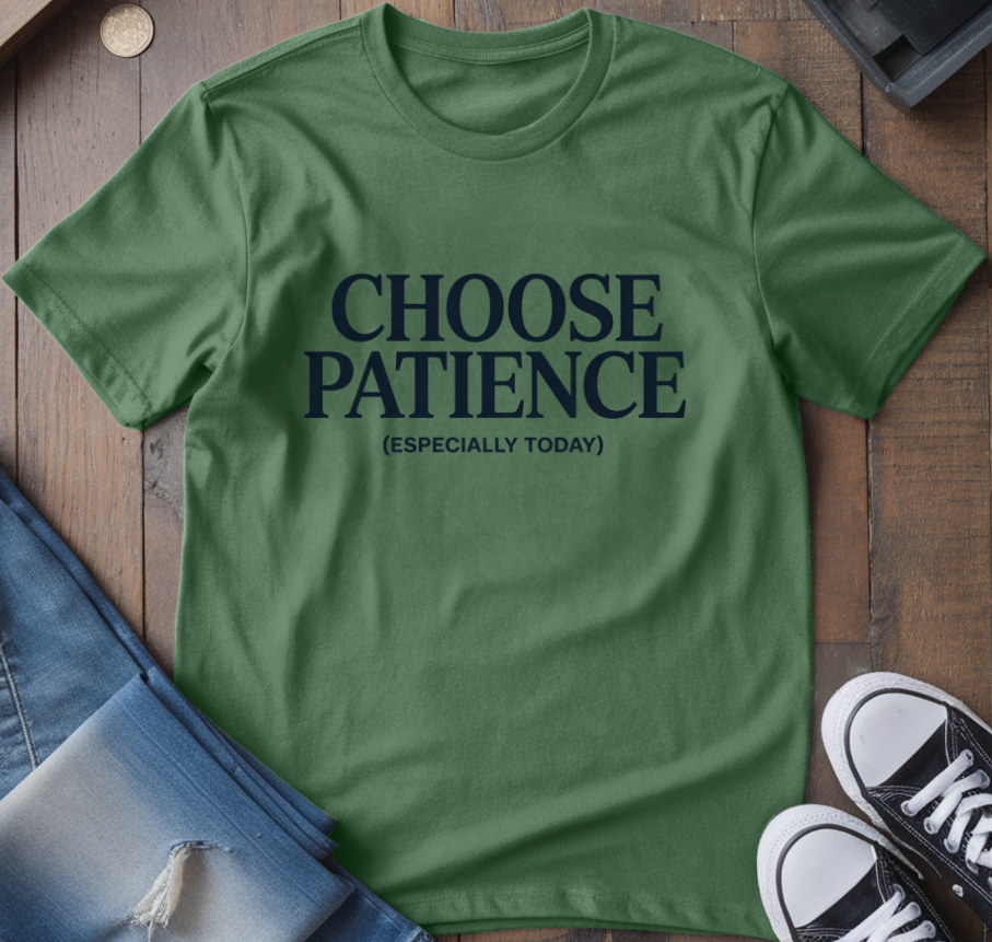 Green t-shirt with 'CHOOSE PATIENCE (ESPECIALLY TODAY)' text on a wooden surface with jeans and sneakers.