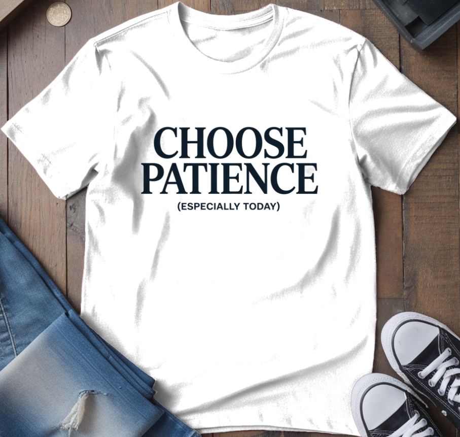 White t-shirt with 'CHOOSE PATIENCE (ESPECIALLY TODAY)' text on a wooden surface with jeans and sneakers.